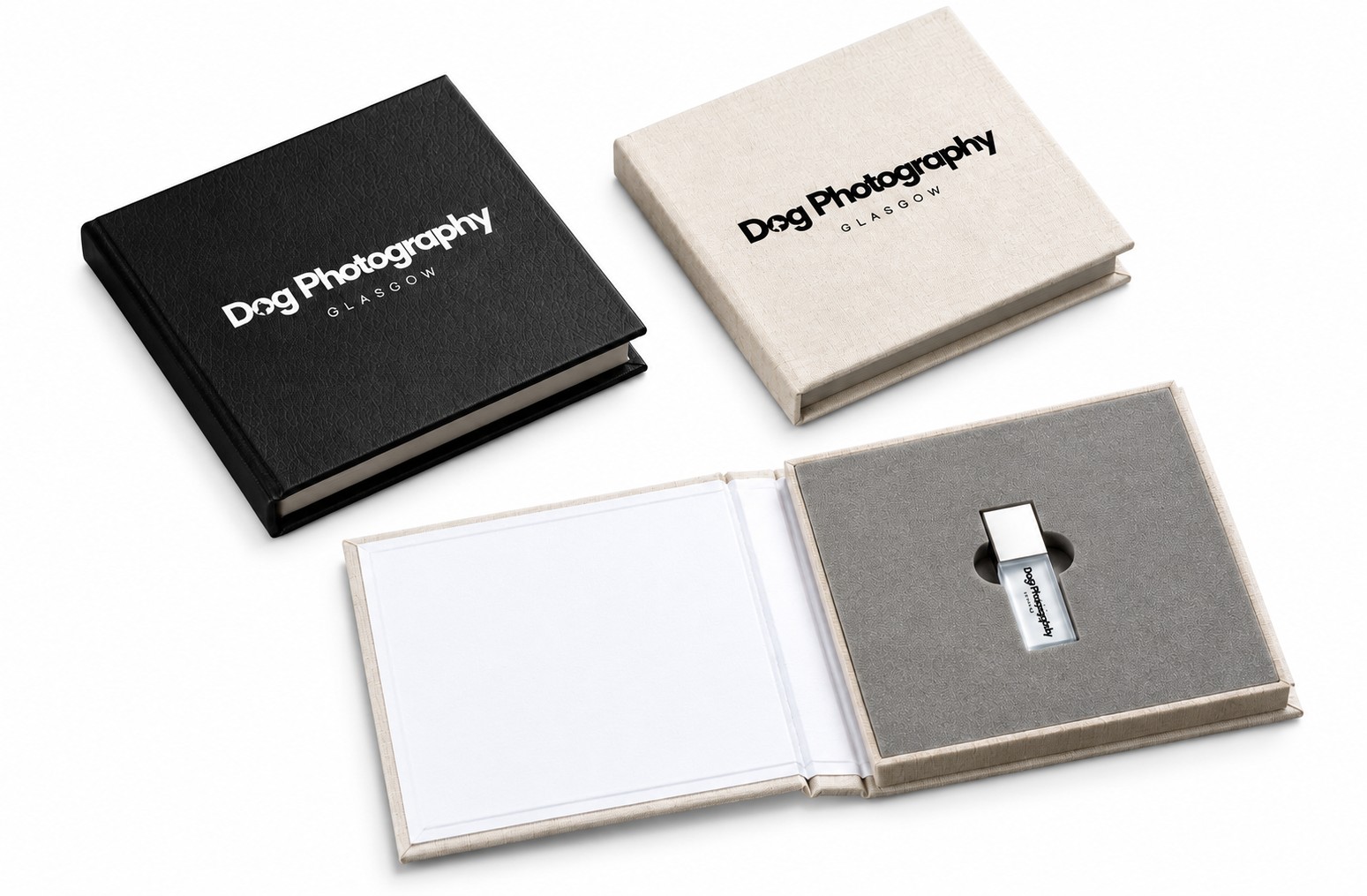 Two personalised presentation cases in black leatherette and cream linen beside an open case revealing a branded crystal USB drive